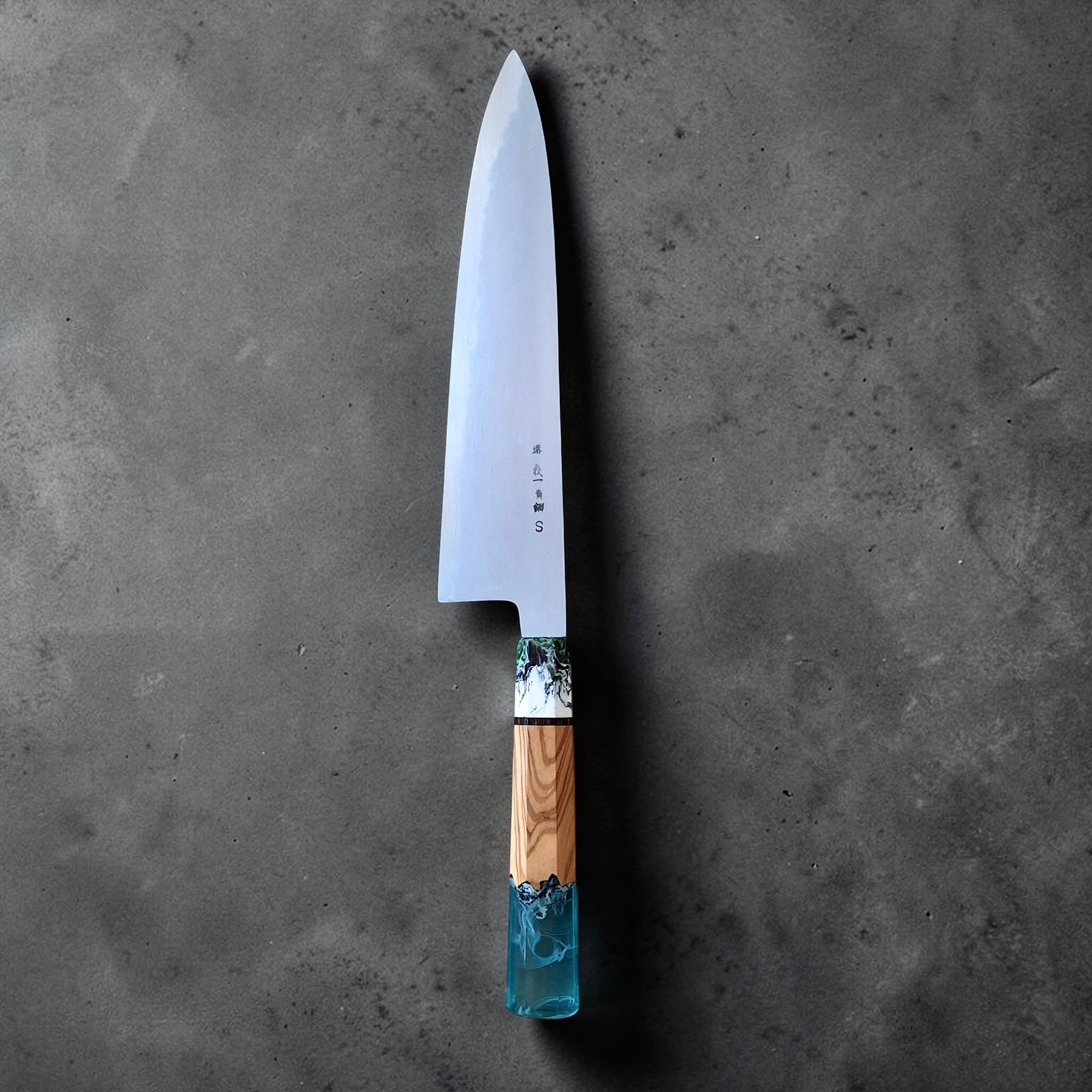 Yoshikazu Tanaka Aogami Super Steel Gyuto 255mm with Prisma knife handle, full blade angled on dark stone background.