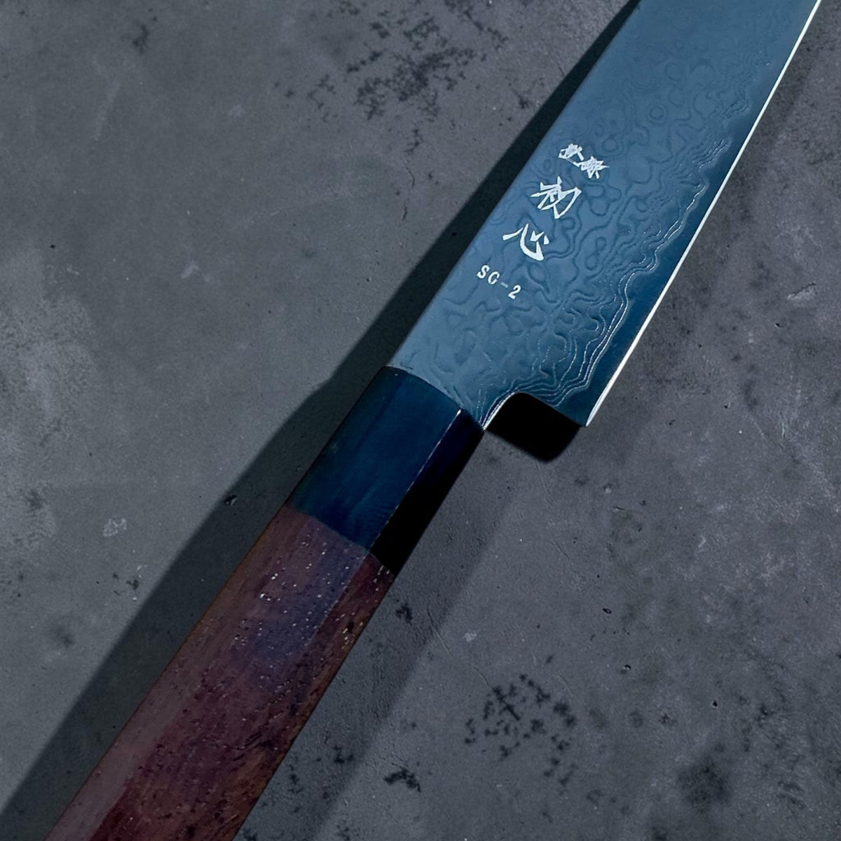 Hatsukokoro Ryuhyo SG2 black Damascus petty 150mm: Close-up of SG2 marking, black Damascus pattern and walnut handle