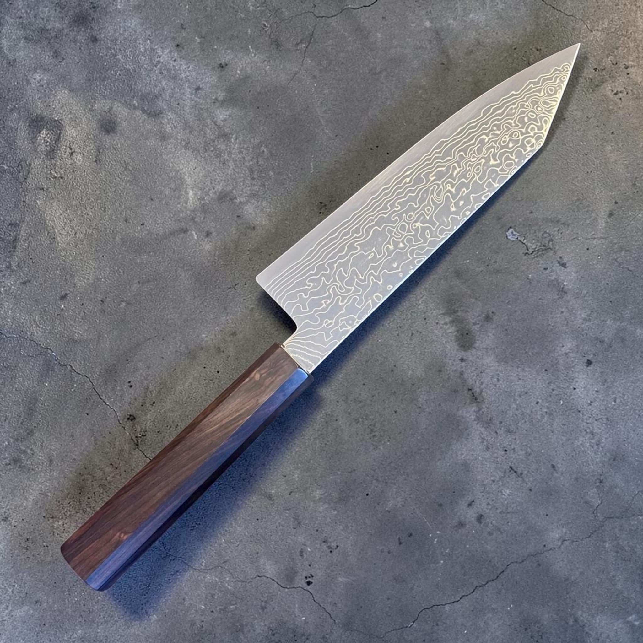 Hatsukokoro Ryuhyo SG2 Damascus Migaki Bunka with Mono Ebony Handle, angled reverse view showing the Damascus cladding and mono ebony handle.