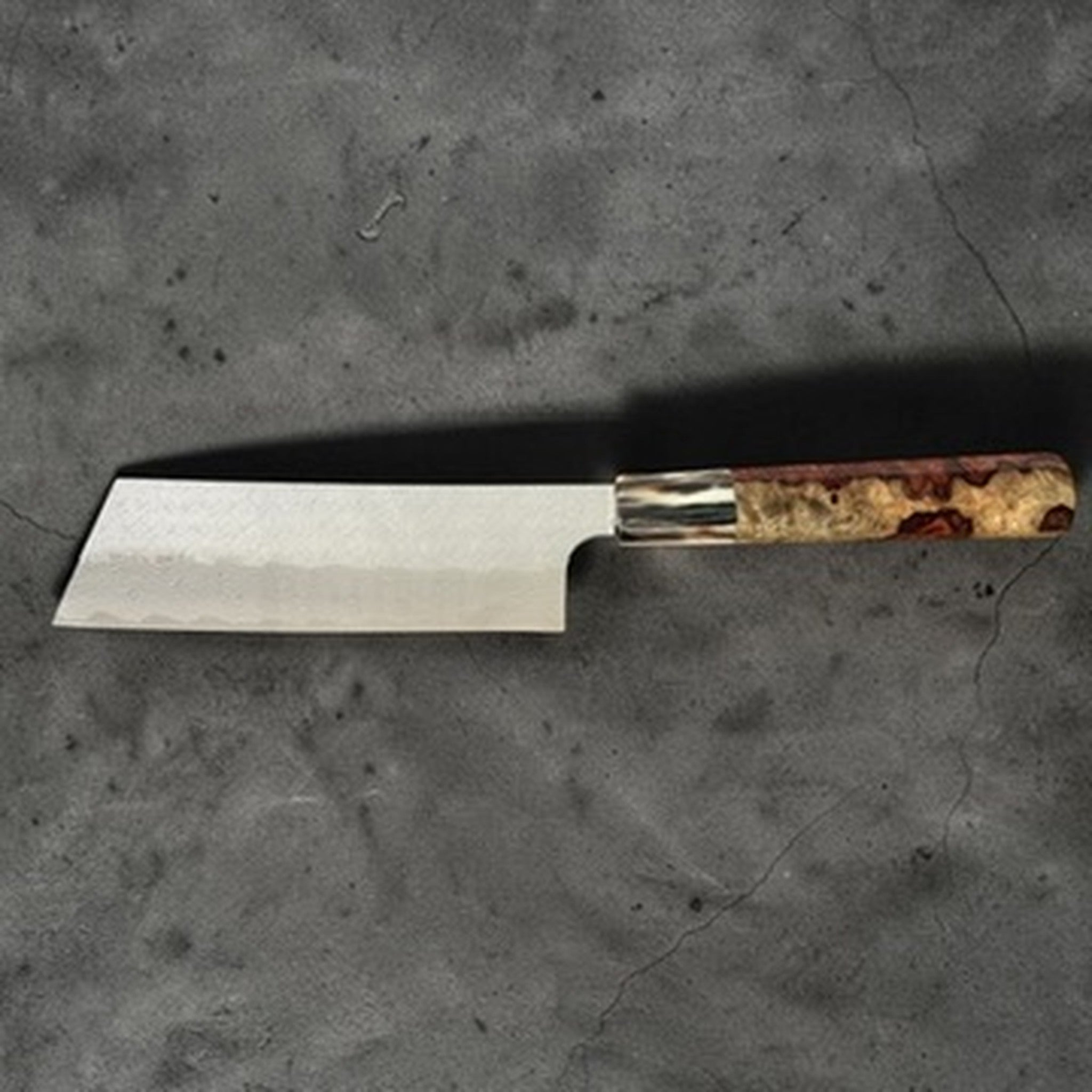 Nigara SG-STRIX Damascus Hakata Kiritsuke Nakiri with Amboyna Burl Handle, left-side profile view showing the Damascus blade face and amboyna burl handle.