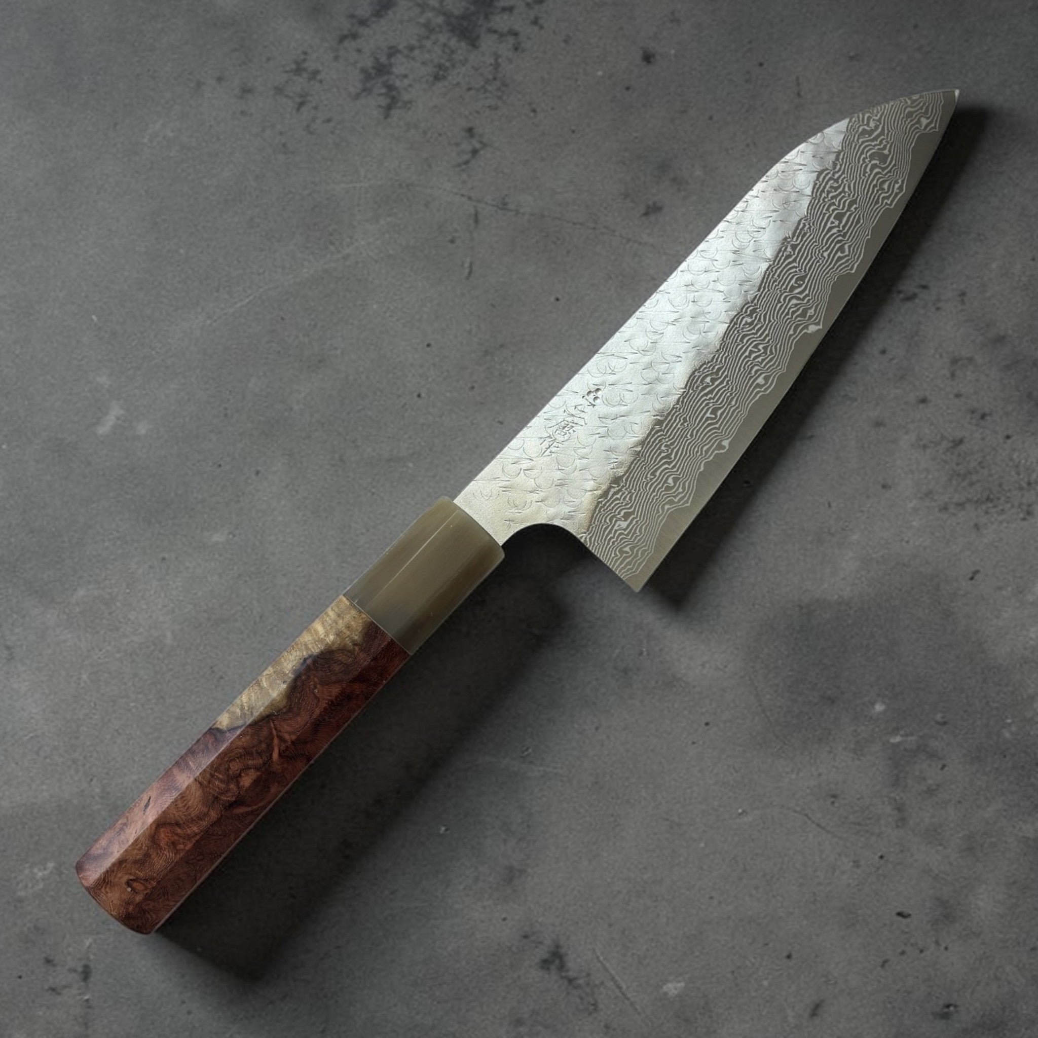 Nigara SG-STRIX Tsuchime Damascus Santoku 165 mm with Amboyna burl and horn handle, angled full-knife product view.