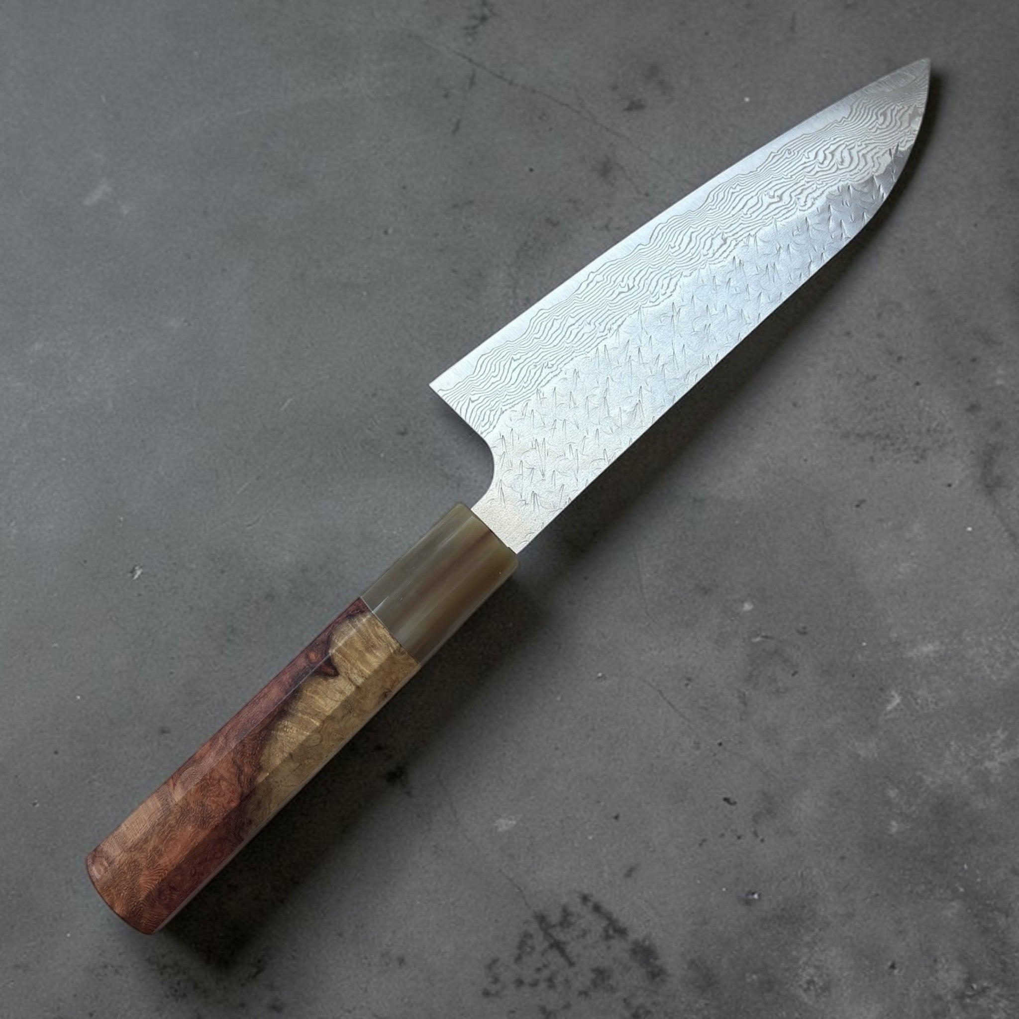 Nigara SG-STRIX Tsuchime Damascus Santoku 165 mm, close angled view of blade pattern and Amboyna burl handle.