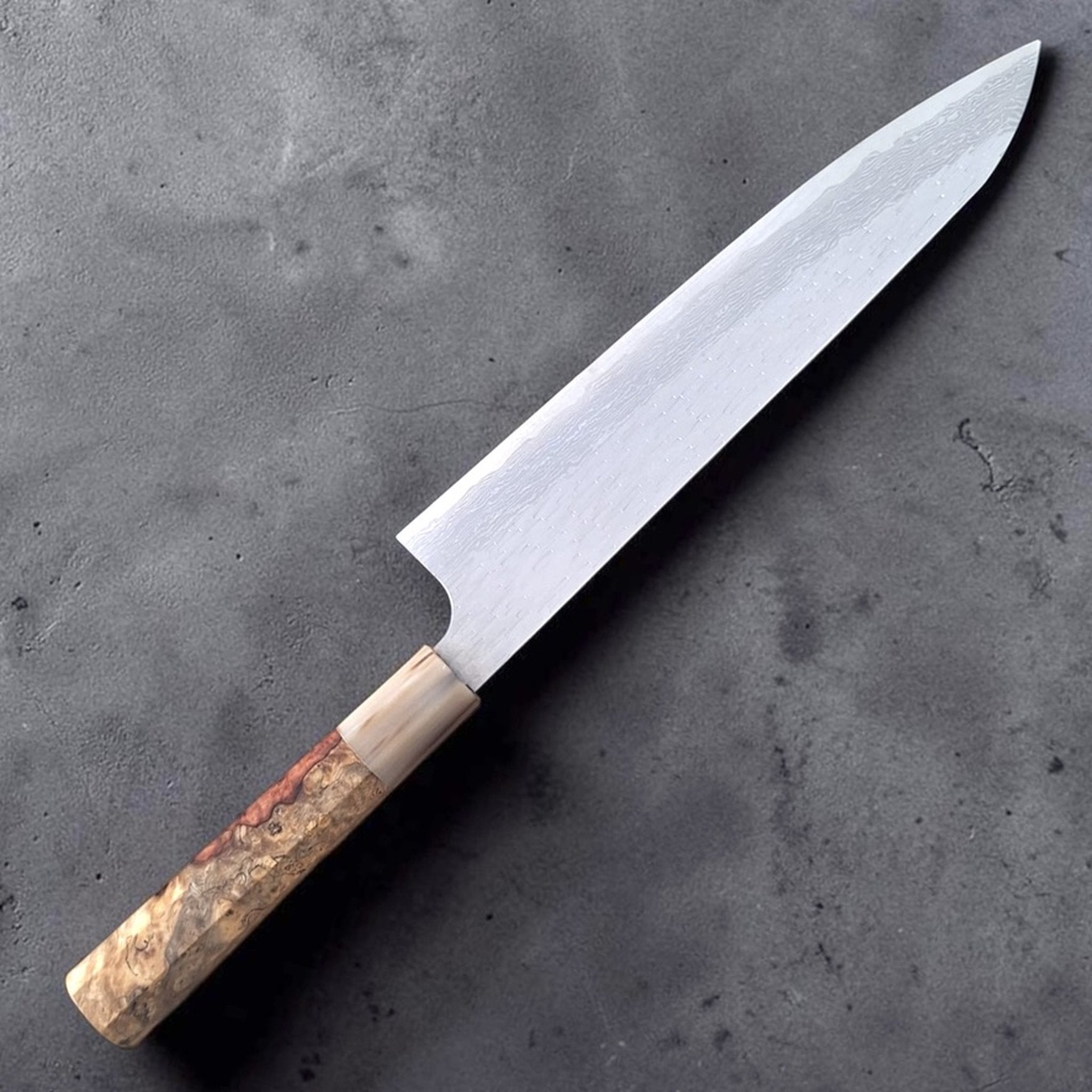 Nigara VG-XEOS Gyuto 240 mm with Amboyna burl handle, angled product photo highlighting the blade finish and custom handle.