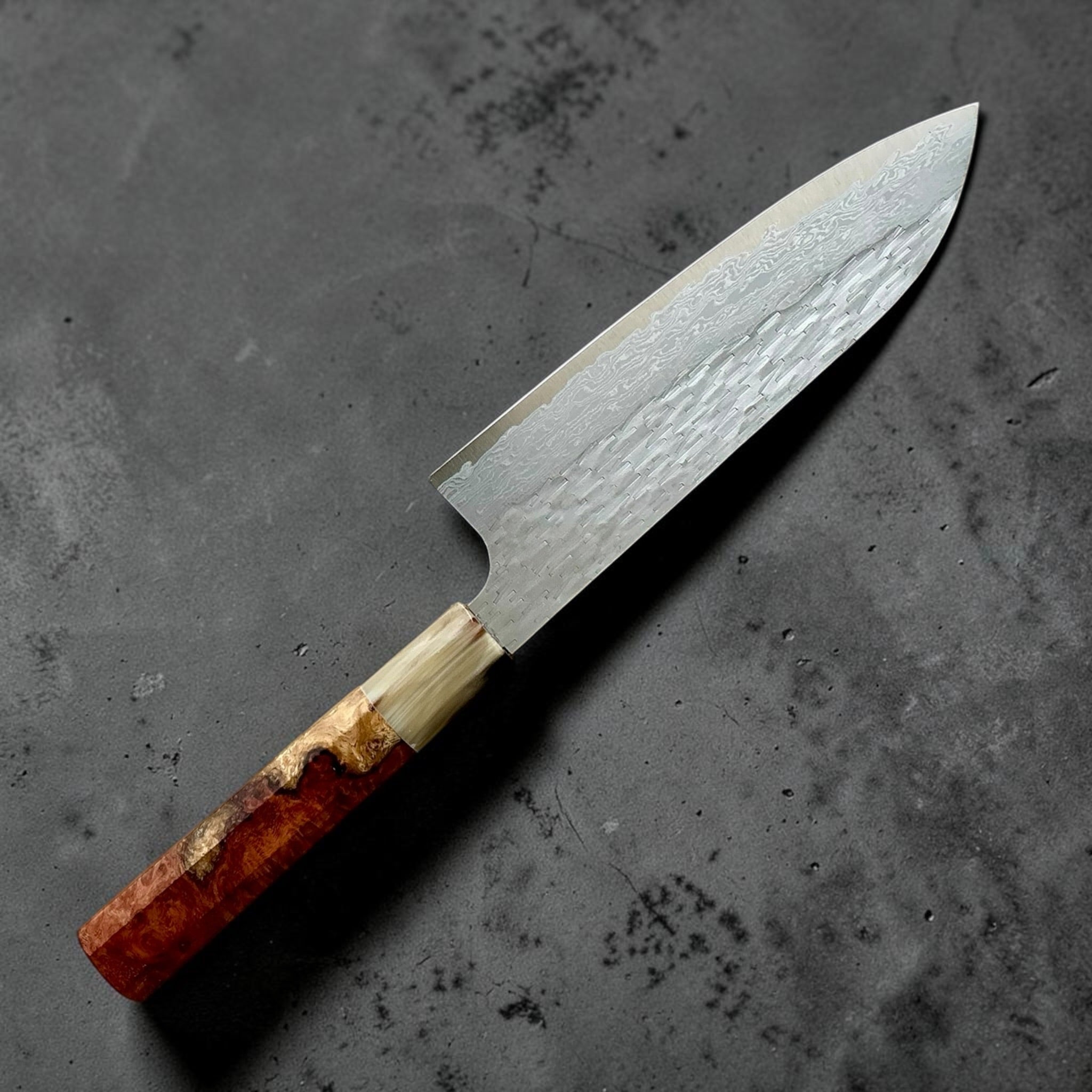 Nigara VG-XEOS polished tsuchime santoku 170mm, angled reverse view highlighting Damascus layers and custom handle.