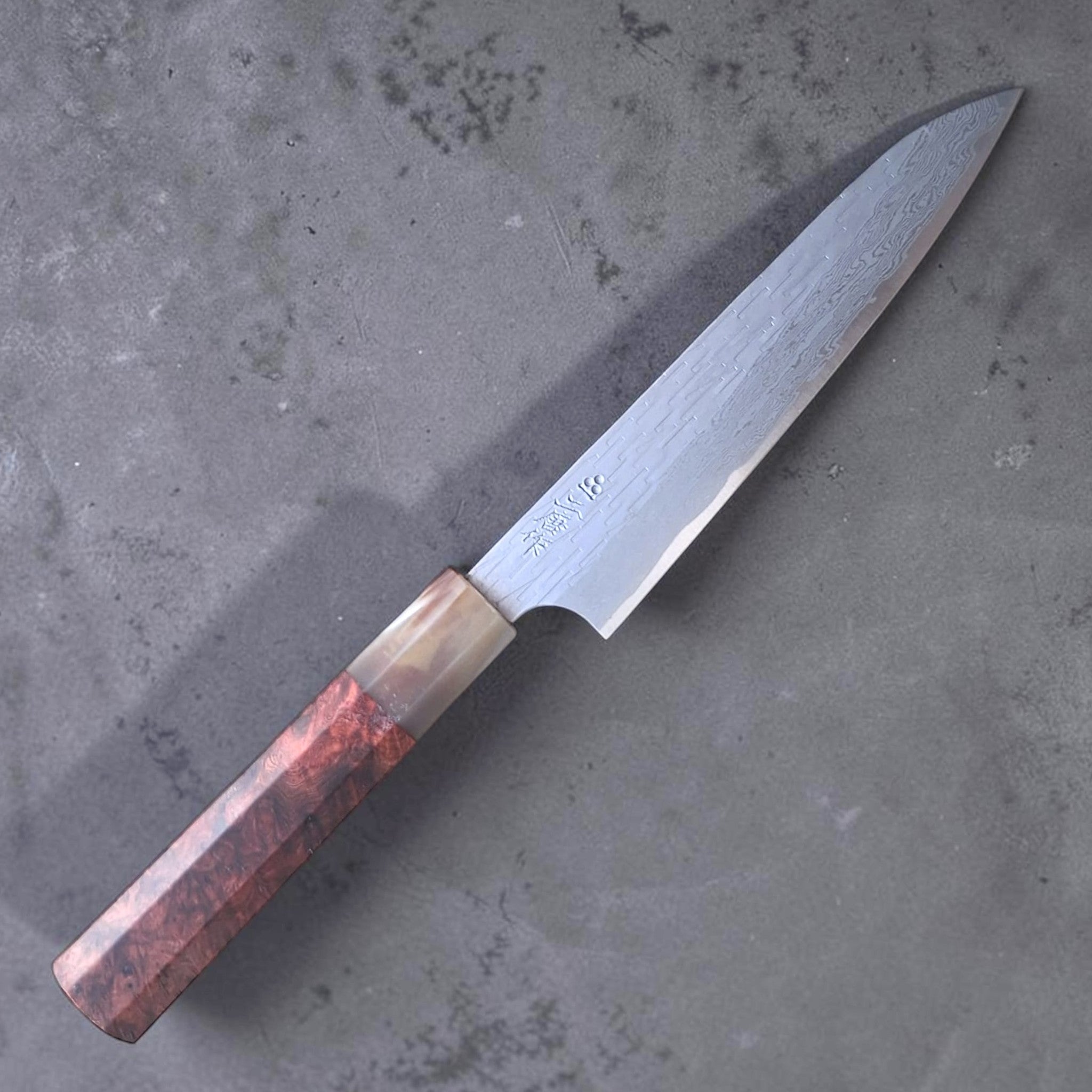 Three-quarter view highlighting Damascus pattern and Amboyna Burl handle.