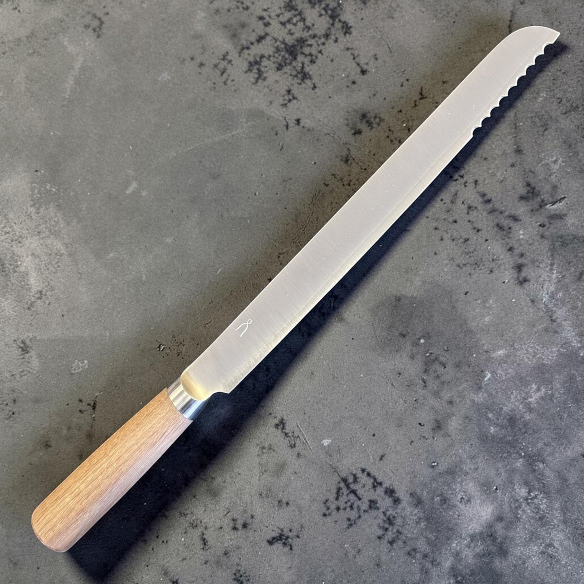 Tadafusa SLD Coltello da pane con manico in legno chiaro, vista angolata a profilo completo che mostra la sezione seghettata vicino alla punta.