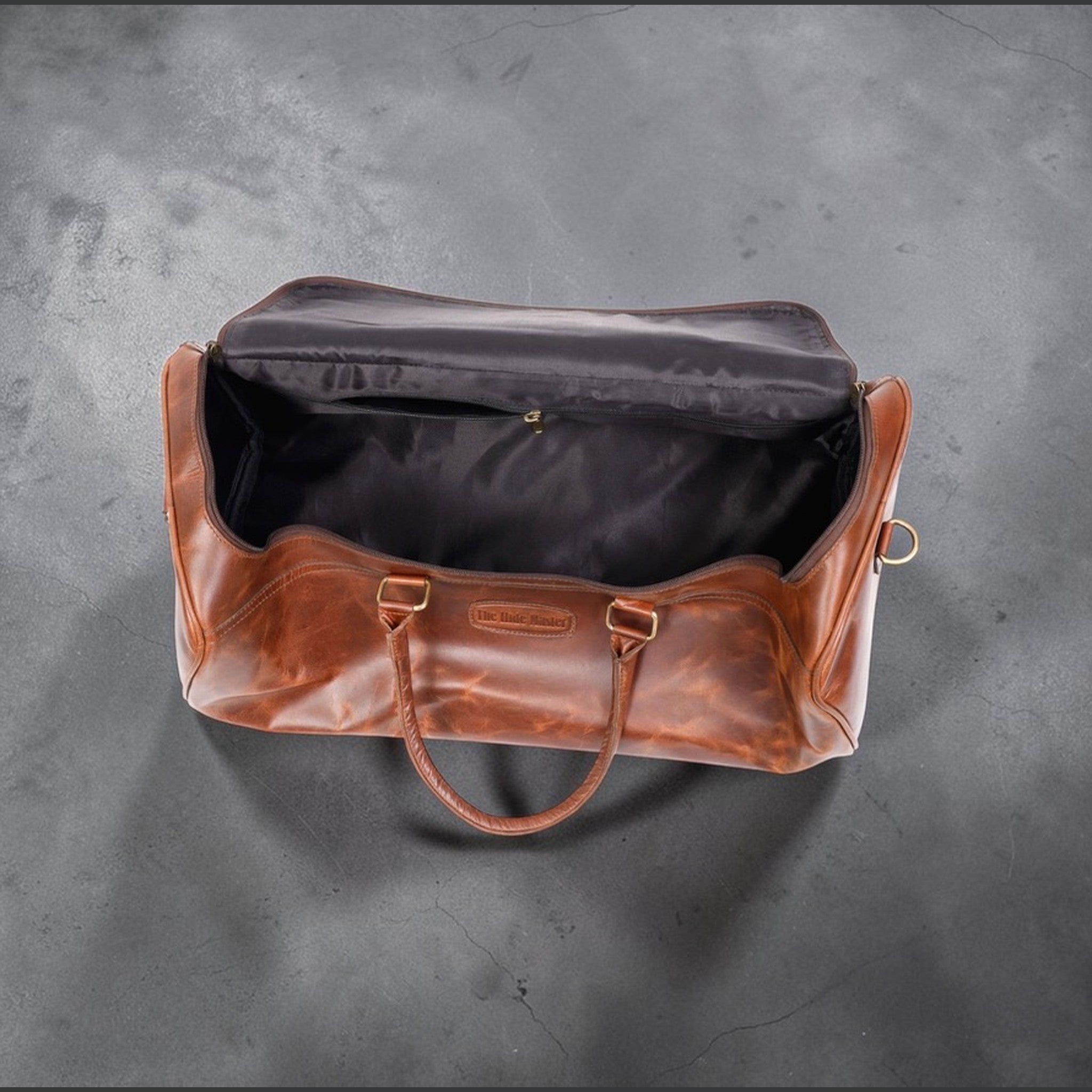 The Hidemaster Aspen Duffle Chef Bag in rustic brown leather, open top view showing the black interior compartment.