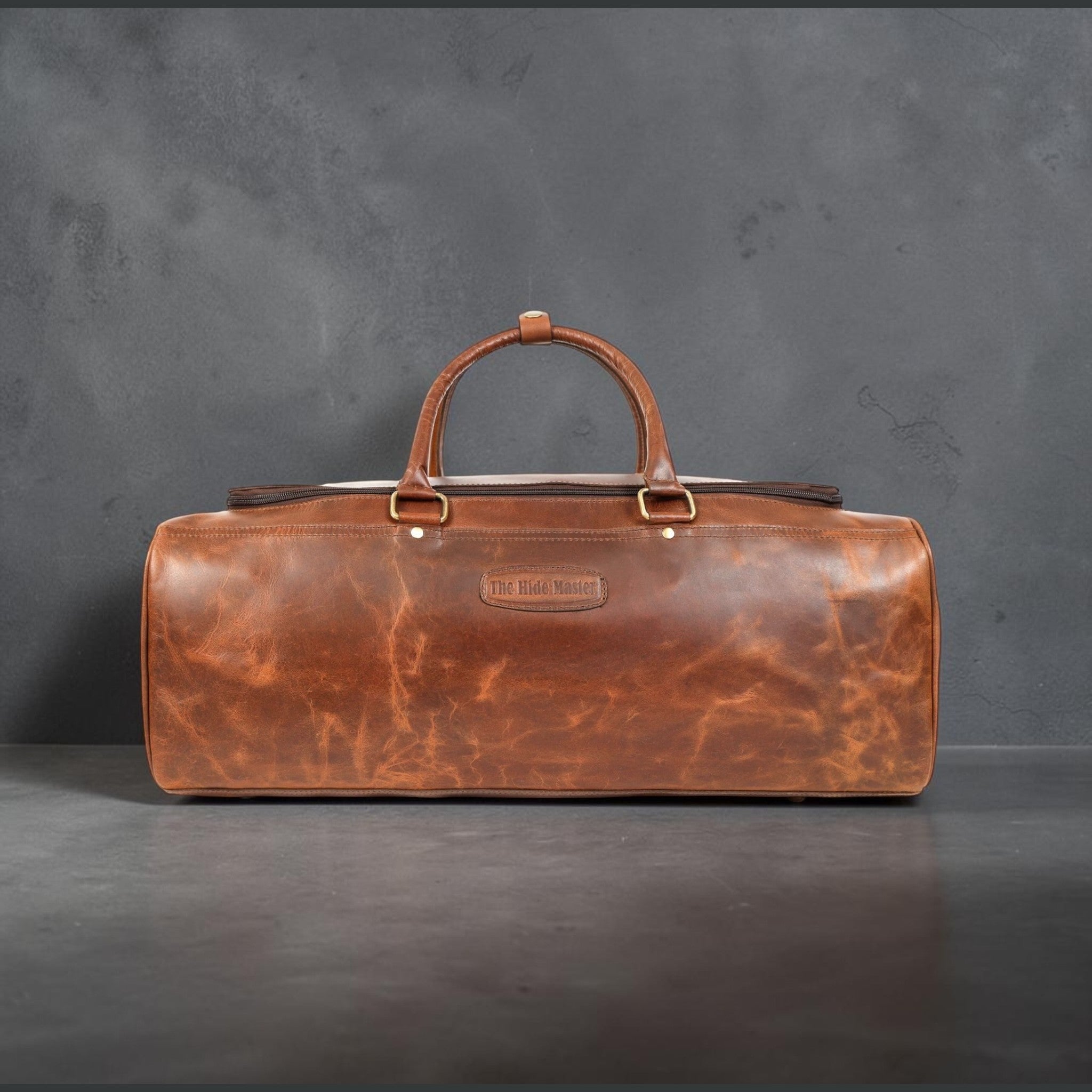 The Hidemaster Aspen Duffle Chef Bag in rustic brown leather, close straight-on side view showing logo patch and marbled leather texture.