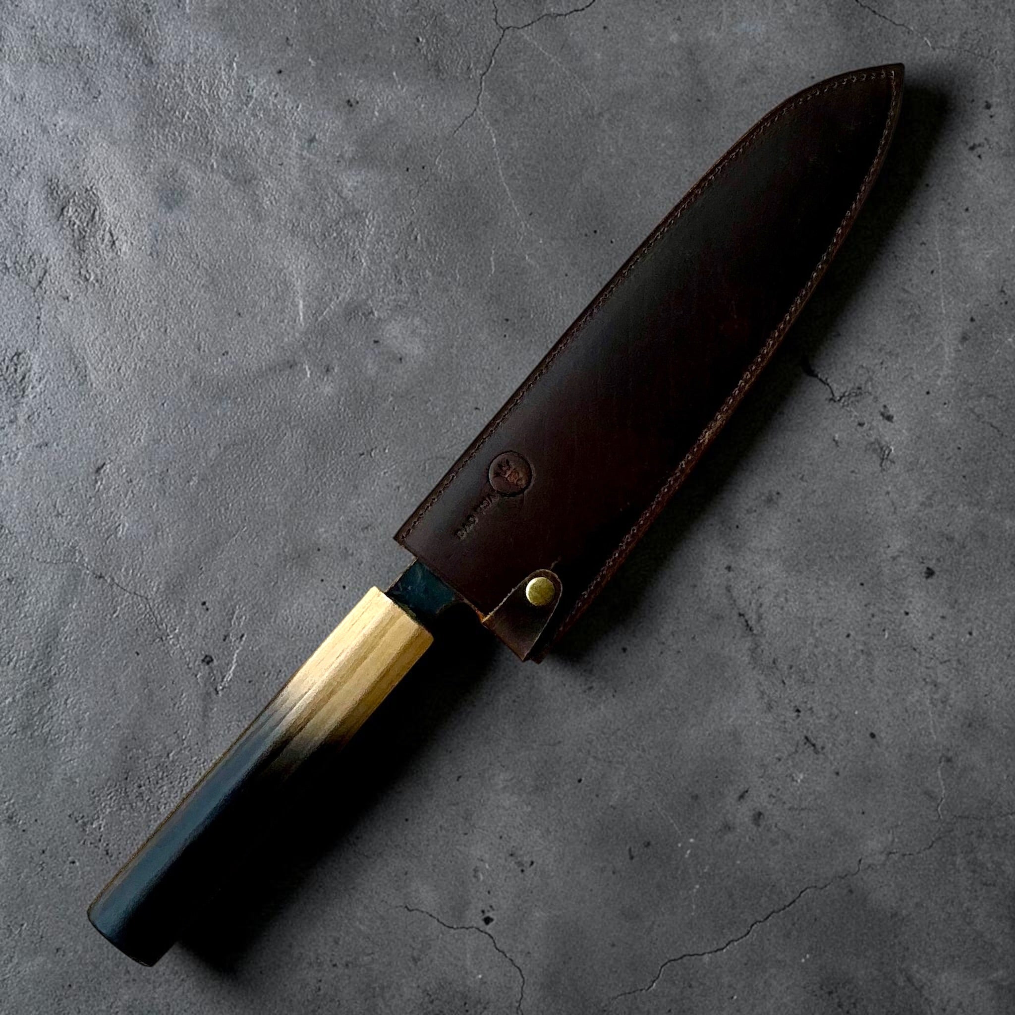 Dao Vua Kuro Tsuchime Gyuto 210mm secured in brown leather sheath