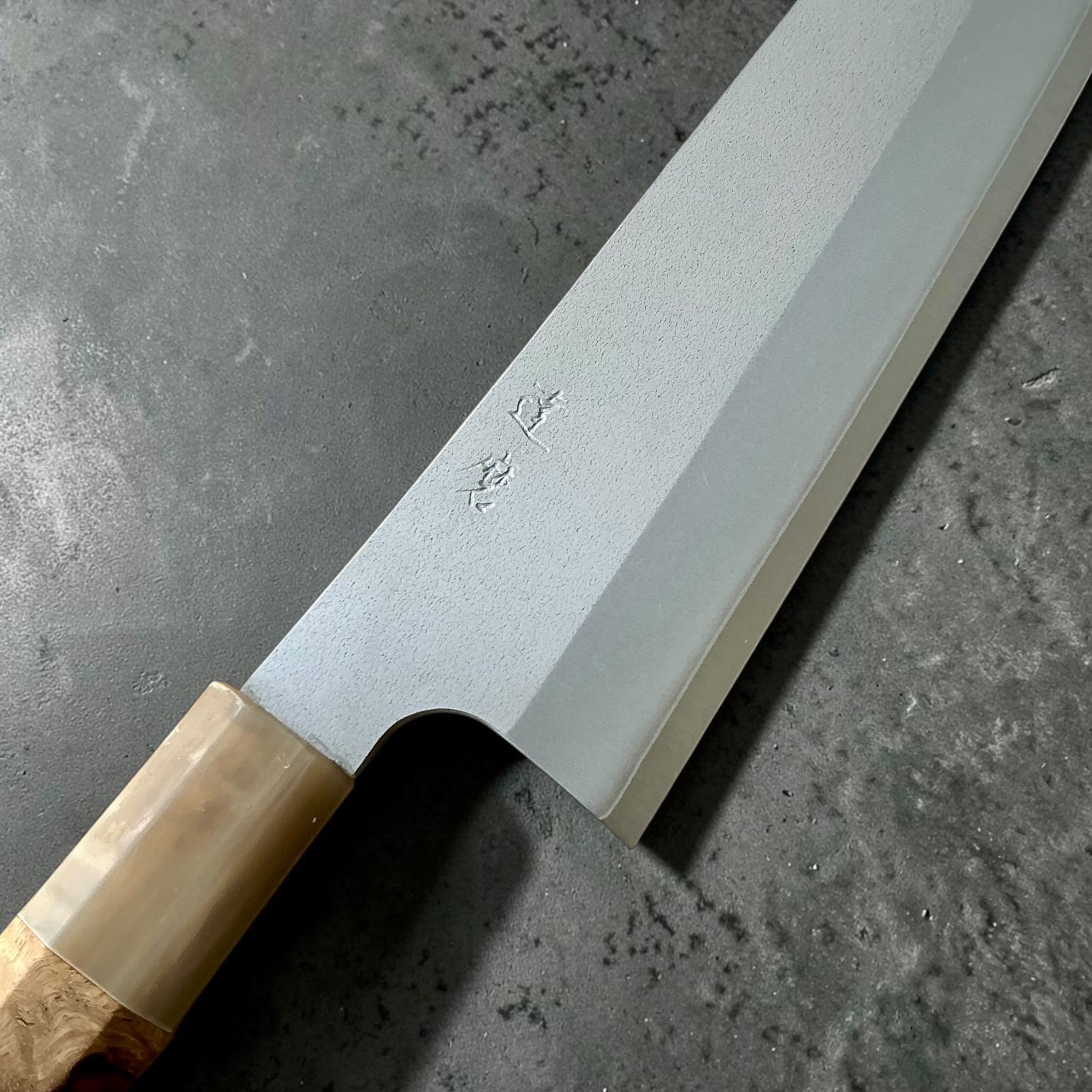 Close-up of Daruma Hamono Ginsan #3 Migaki Gyuto 240mm blade, kanji and Cypress and Horn handle.