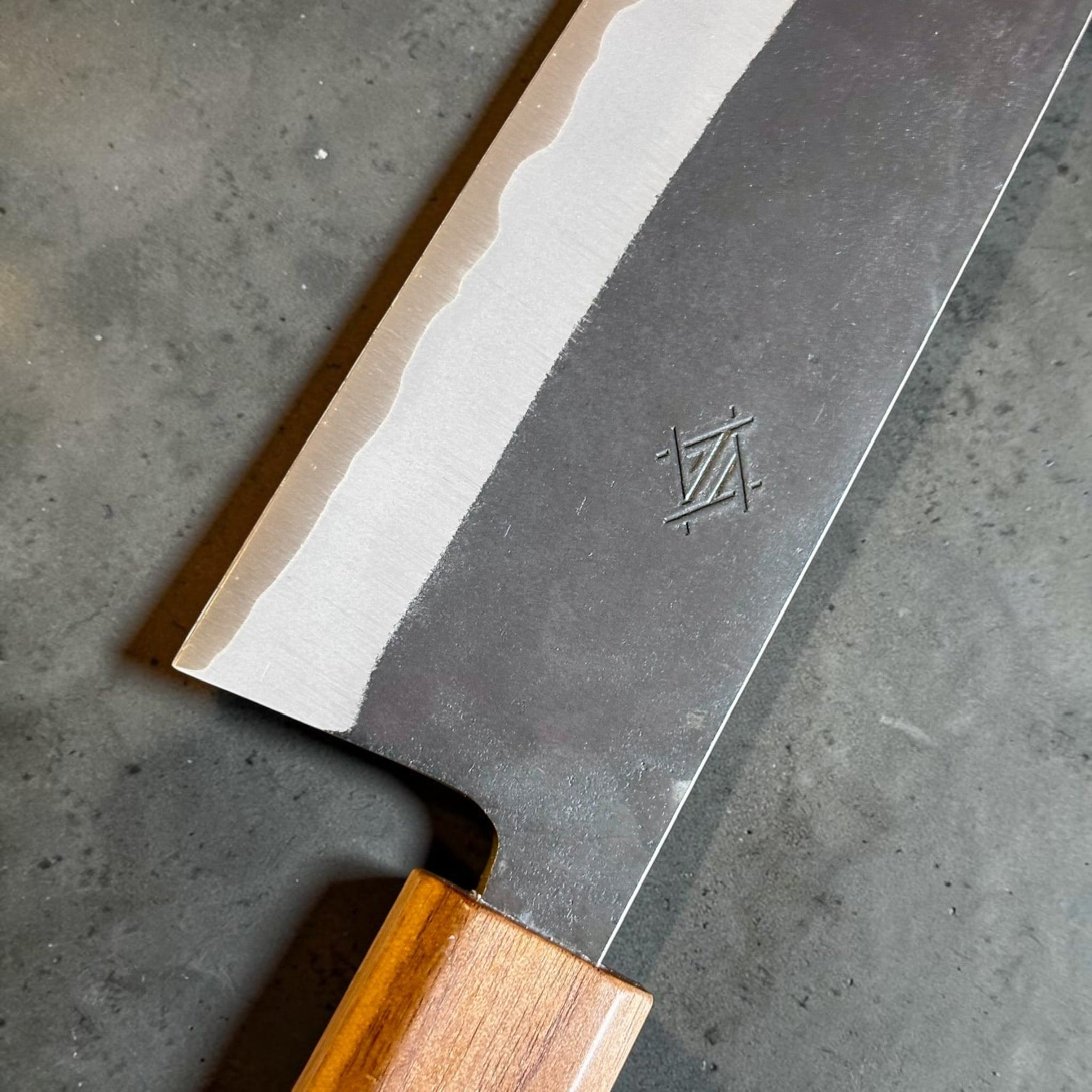 Close-up of the Imai Bunka 183mm kurouchi finish, stainless cladding and polished Aogami Super cutting edge