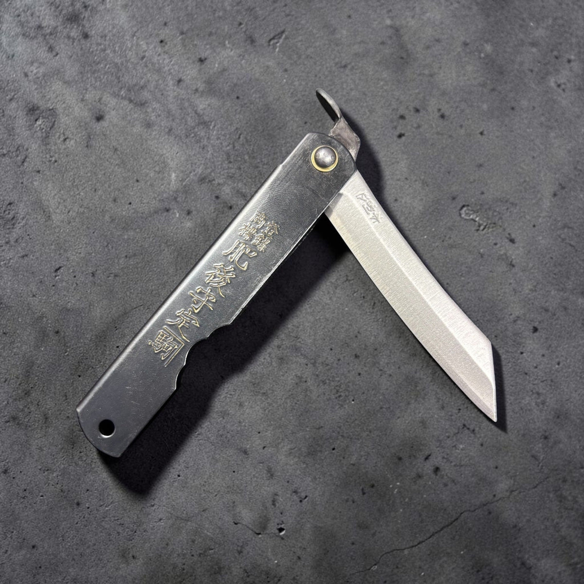 Nagao Higonokami SK carbon steel medium Japanese friction folder, black handle with gold kanji, blade partially open on dark grey background. #size_medium - black