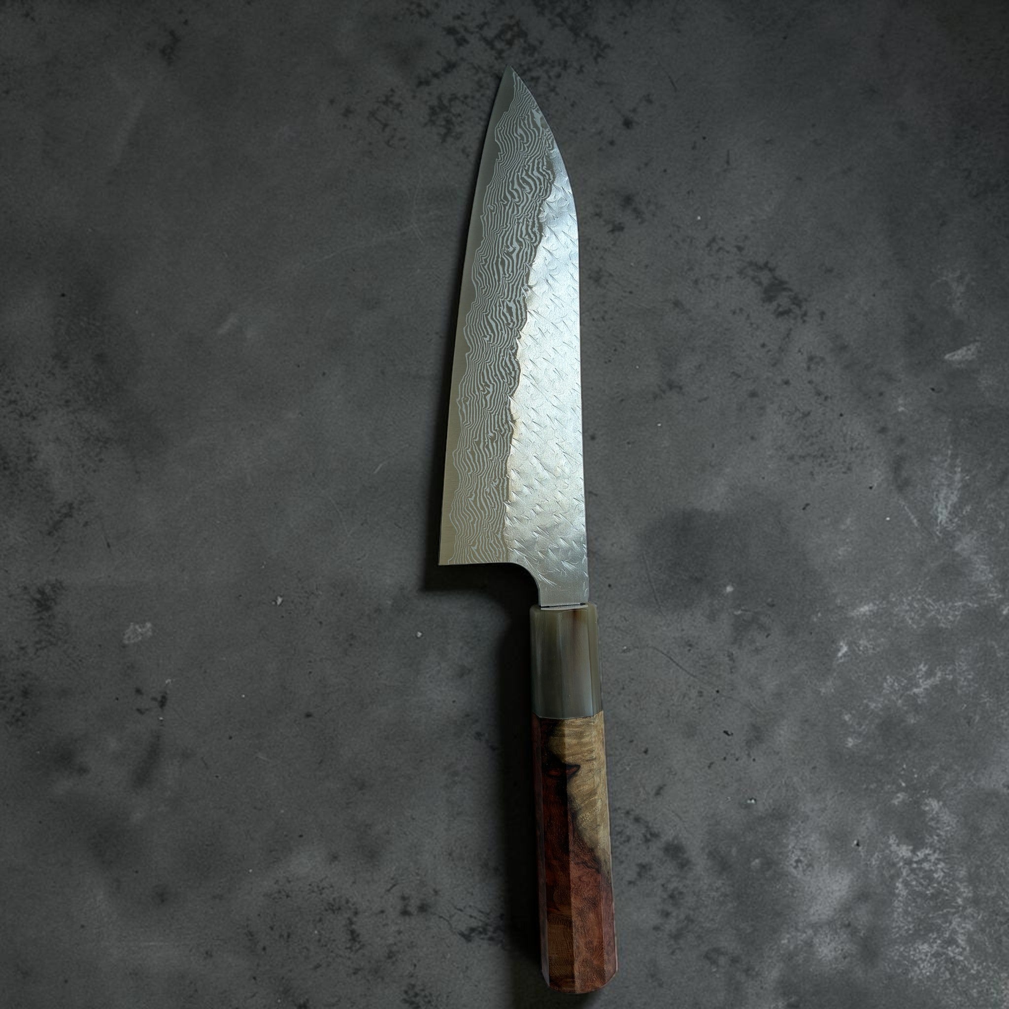 Nigara SG-STRIX Tsuchime Damascus Santoku 165 mm, upright blade view showing hammered texture and Damascus cladding.