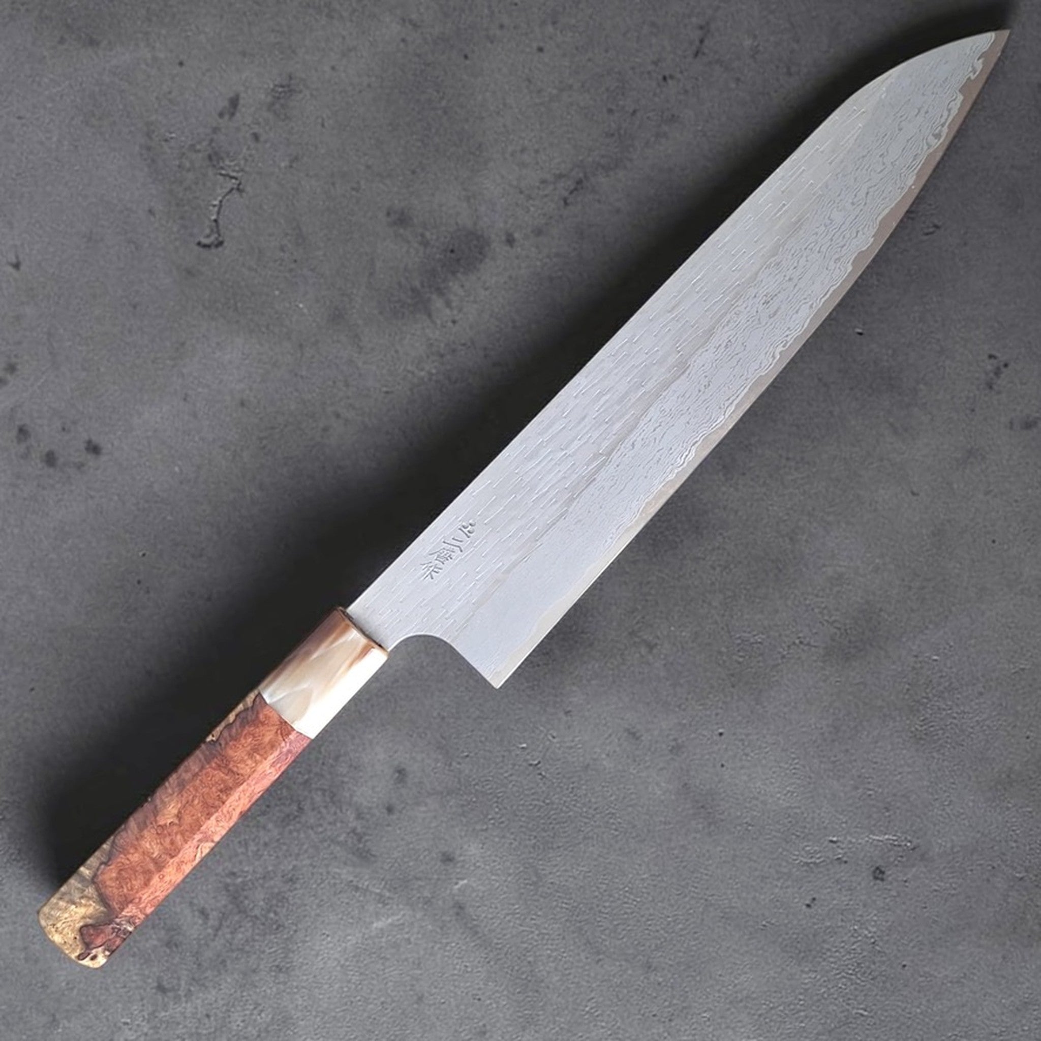 Nigara VG-XEOS Gyuto 240 mm with Amboyna burl handle, full knife view showing the blade profile and layered steel pattern.