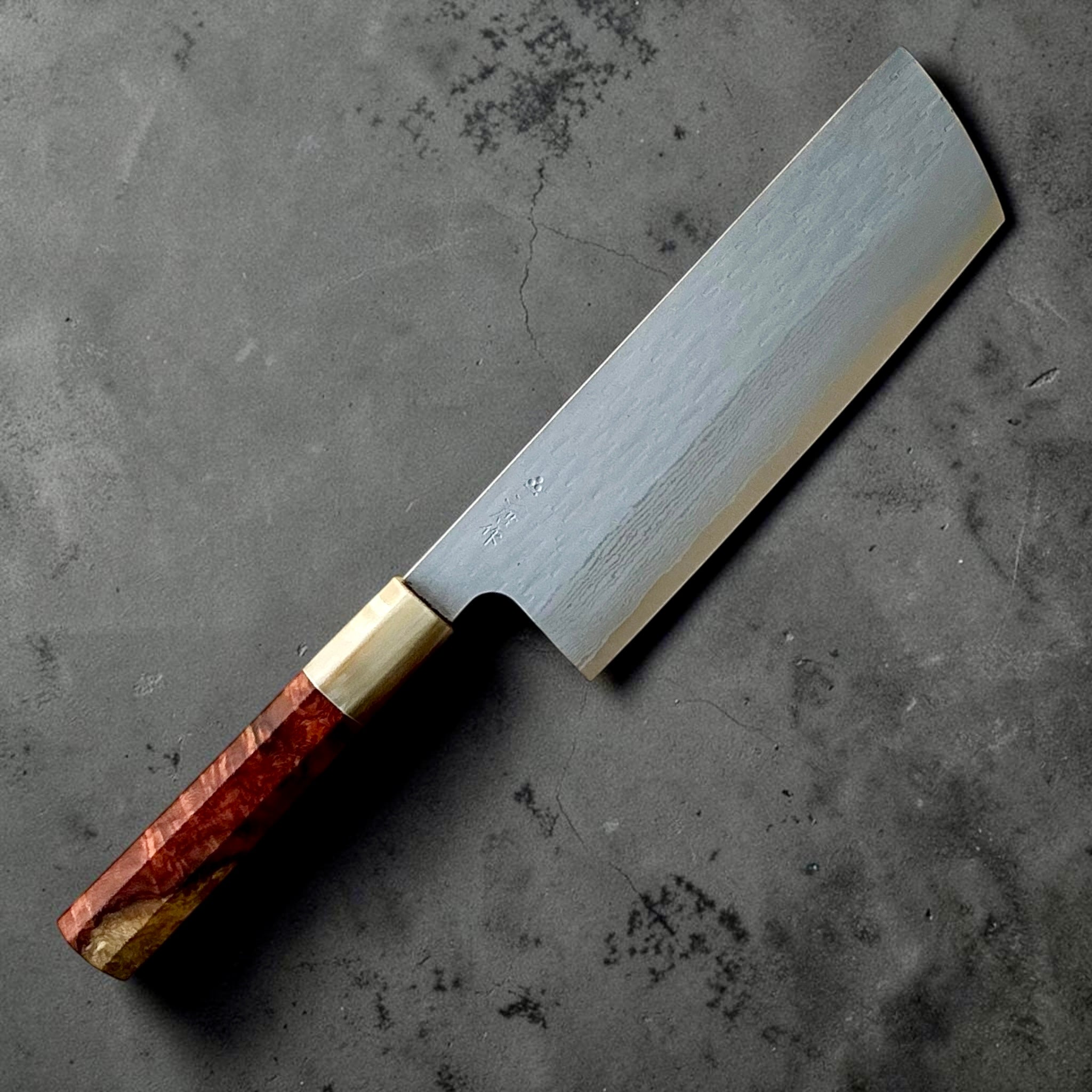 Nigara VG-XEOS polished tsuchime nakiri 165mm, angled view showing Damascus layers and Amboyna burl handle.
