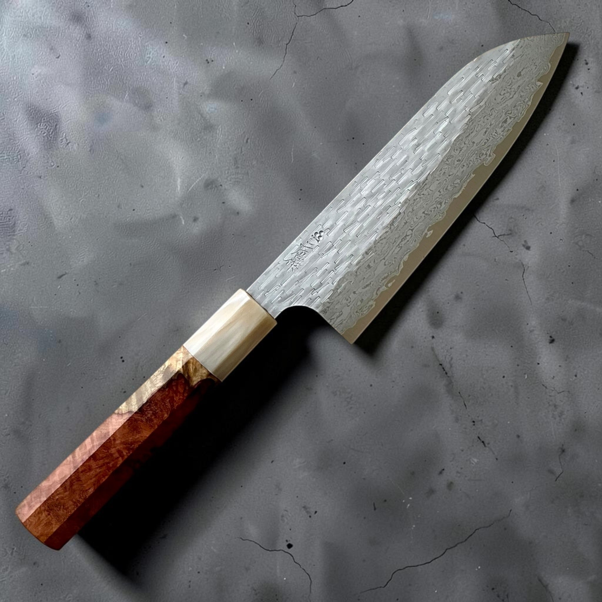 Nigara VG-XEOS polished tsuchime santoku 170mm with Amboyna burl handle, kanji-side angled view.
