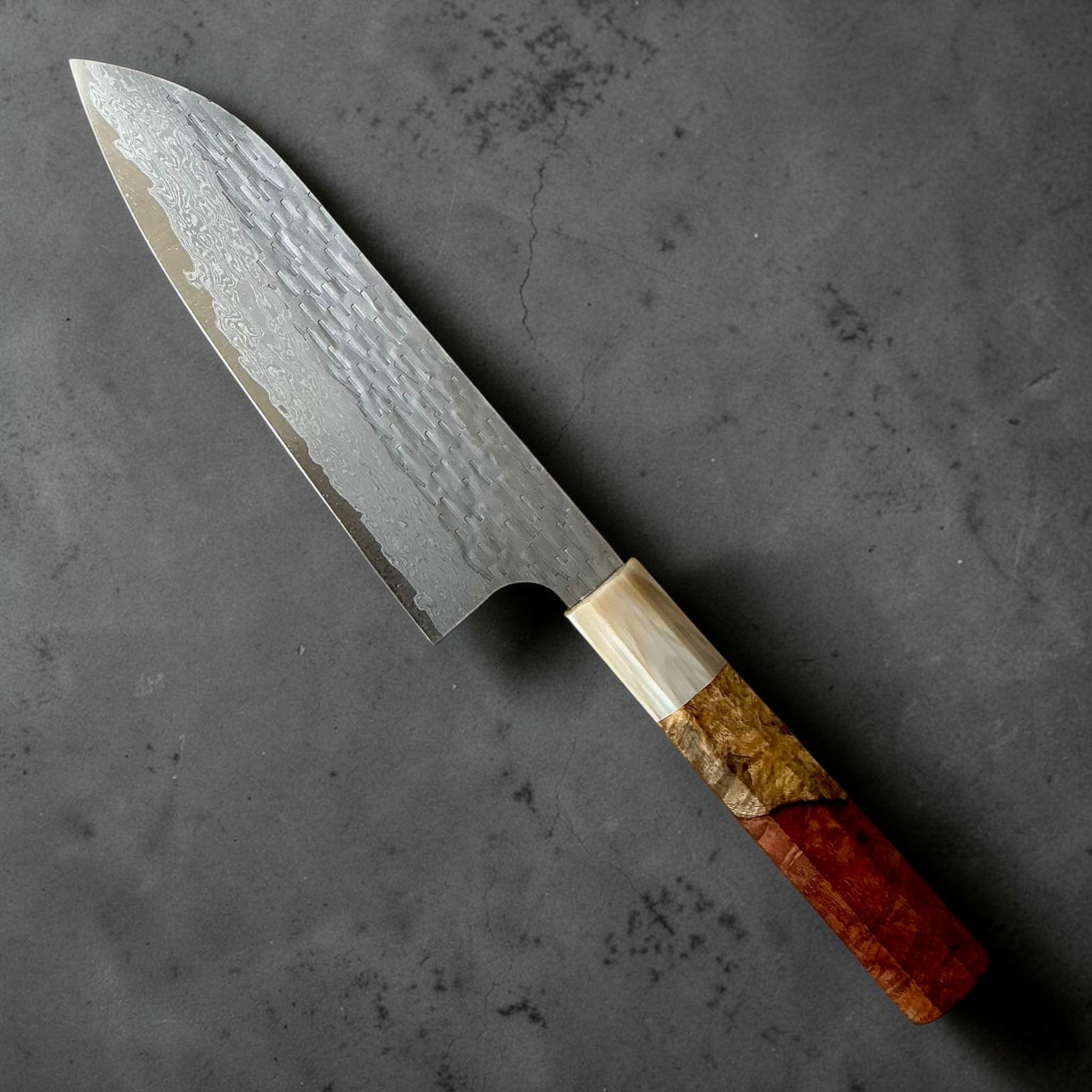 Nigara VG-XEOS polished tsuchime santoku 170mm with Amboyna burl handle, reverse angled view.