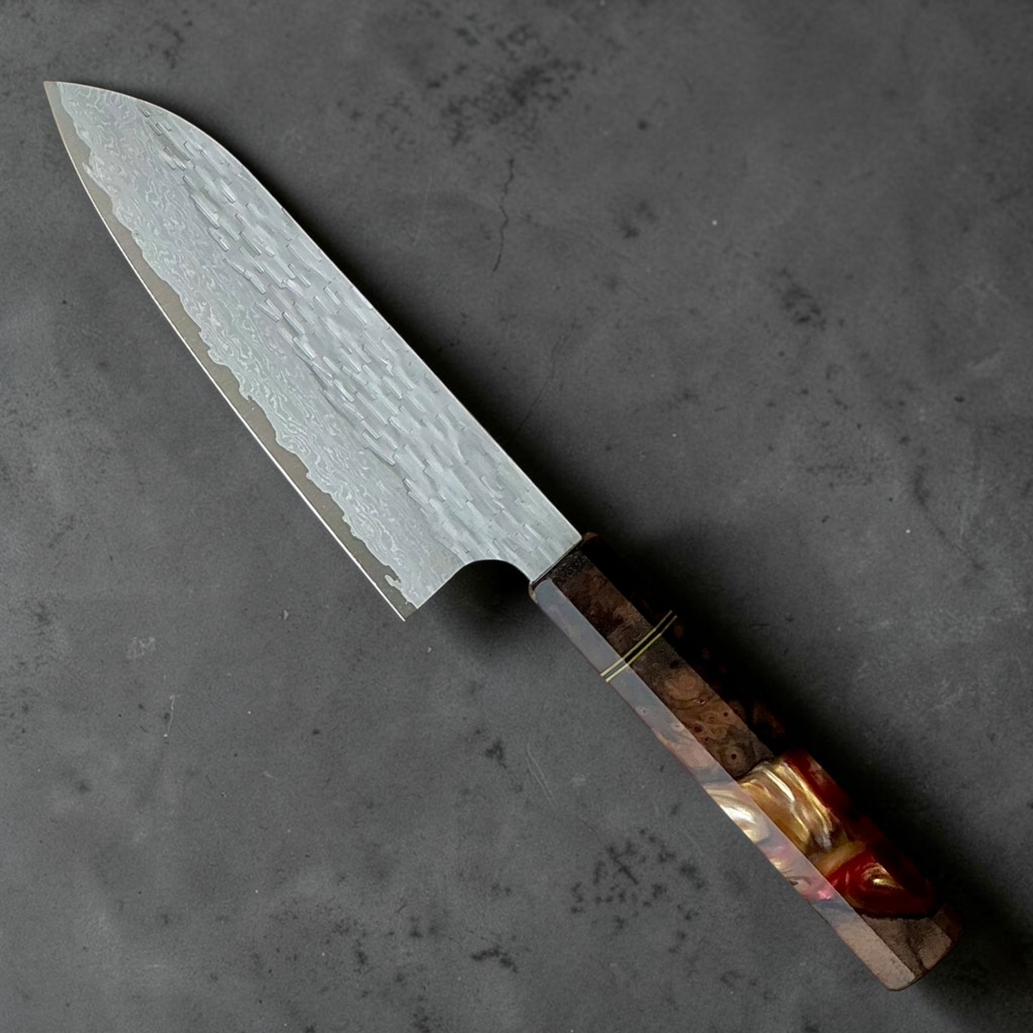 Nigara VG-XEOS polished tsuchime santoku 170mm with red-brown Prisma custom handle, angled view.
