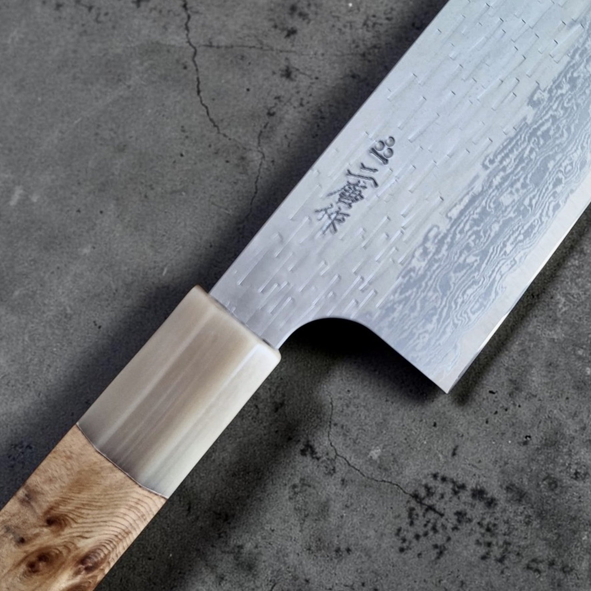 Nigara VG XEOS Tsuchime Gyuto 240 mm, close-up of maker’s mark, tsuchime texture, Damascus edge pattern, cypress and horn handle.