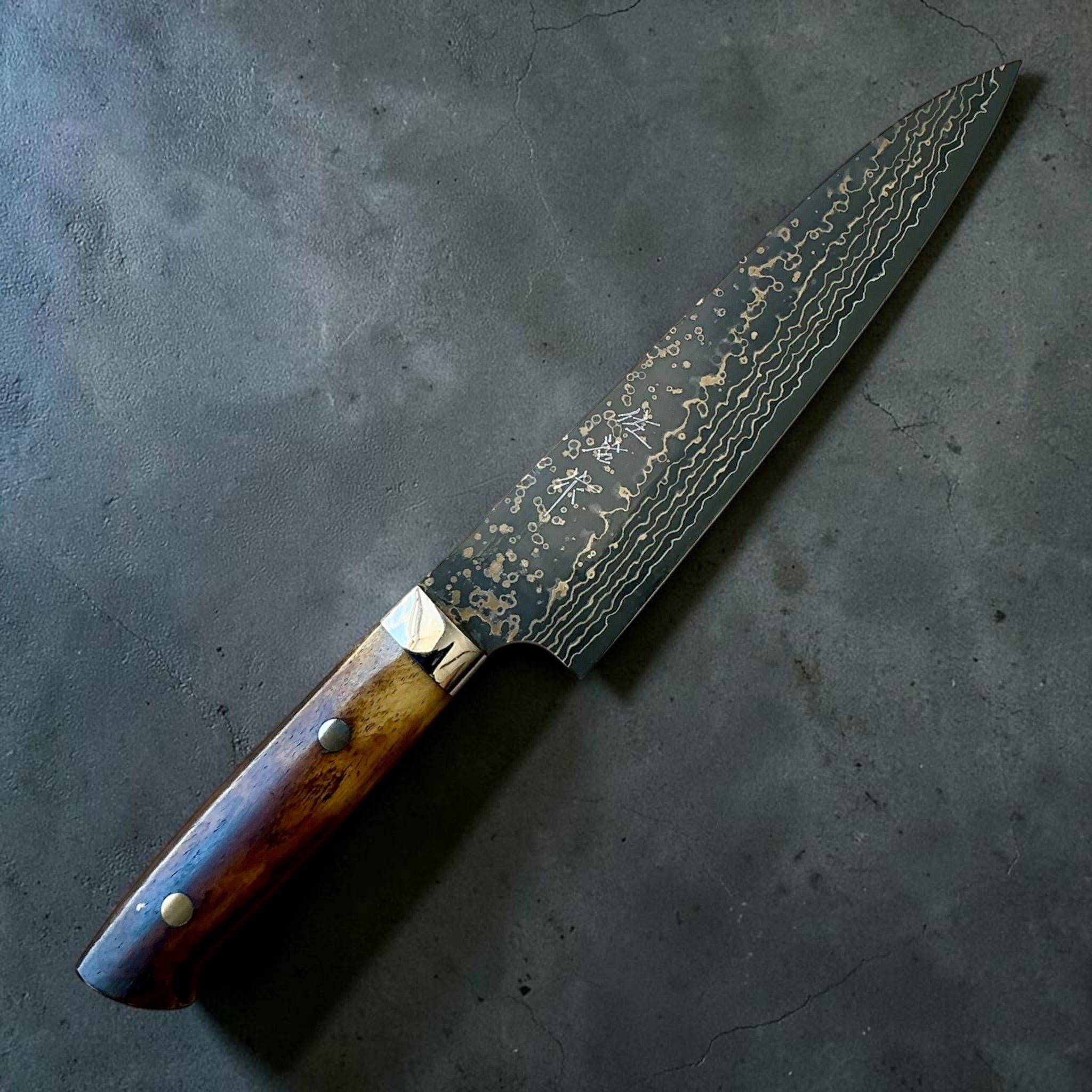 Takeshi Saji VG-10W Gold Damascus Gyuto 180 mm, dettaglio angolato della lama e del manico in osso bovino.