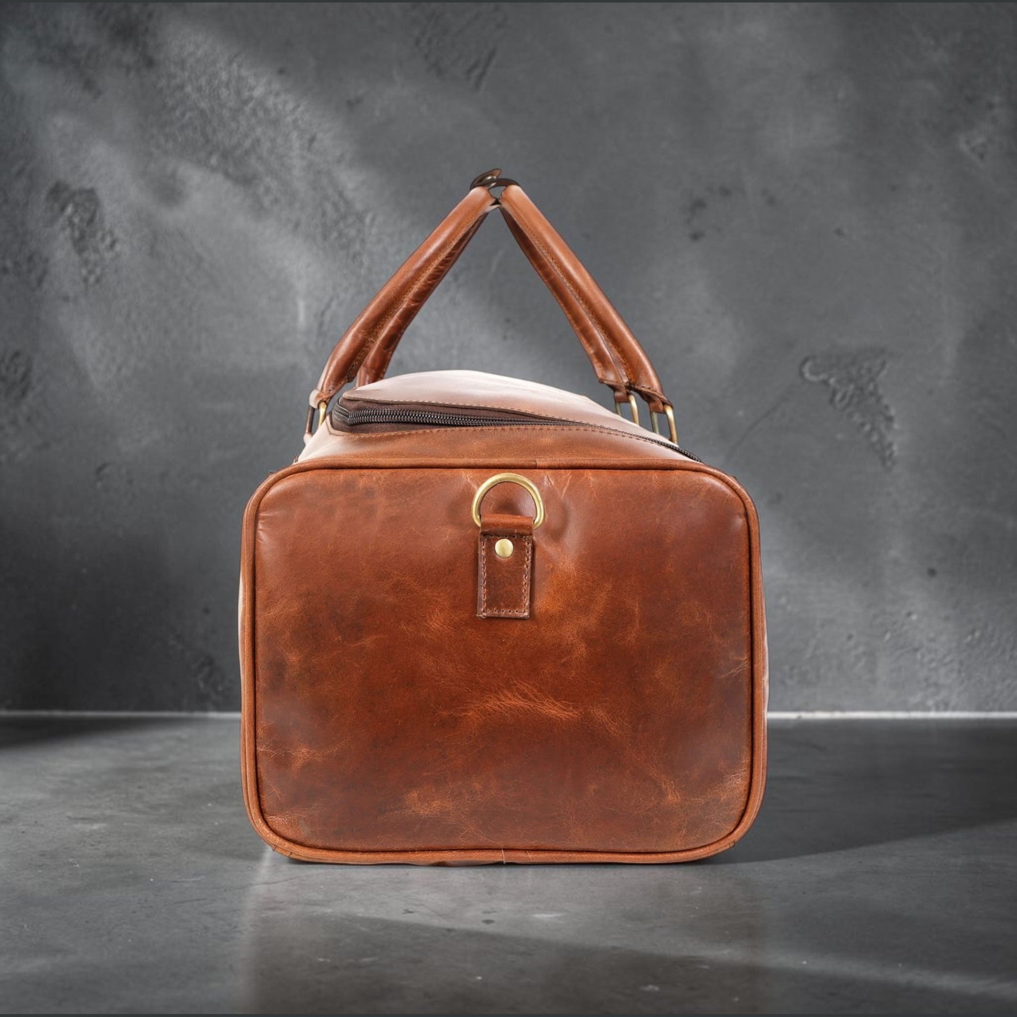 The Hidemaster Aspen Duffle Chef Bag in rustic brown leather, end view showing brass hardware and structured rectangular shape.