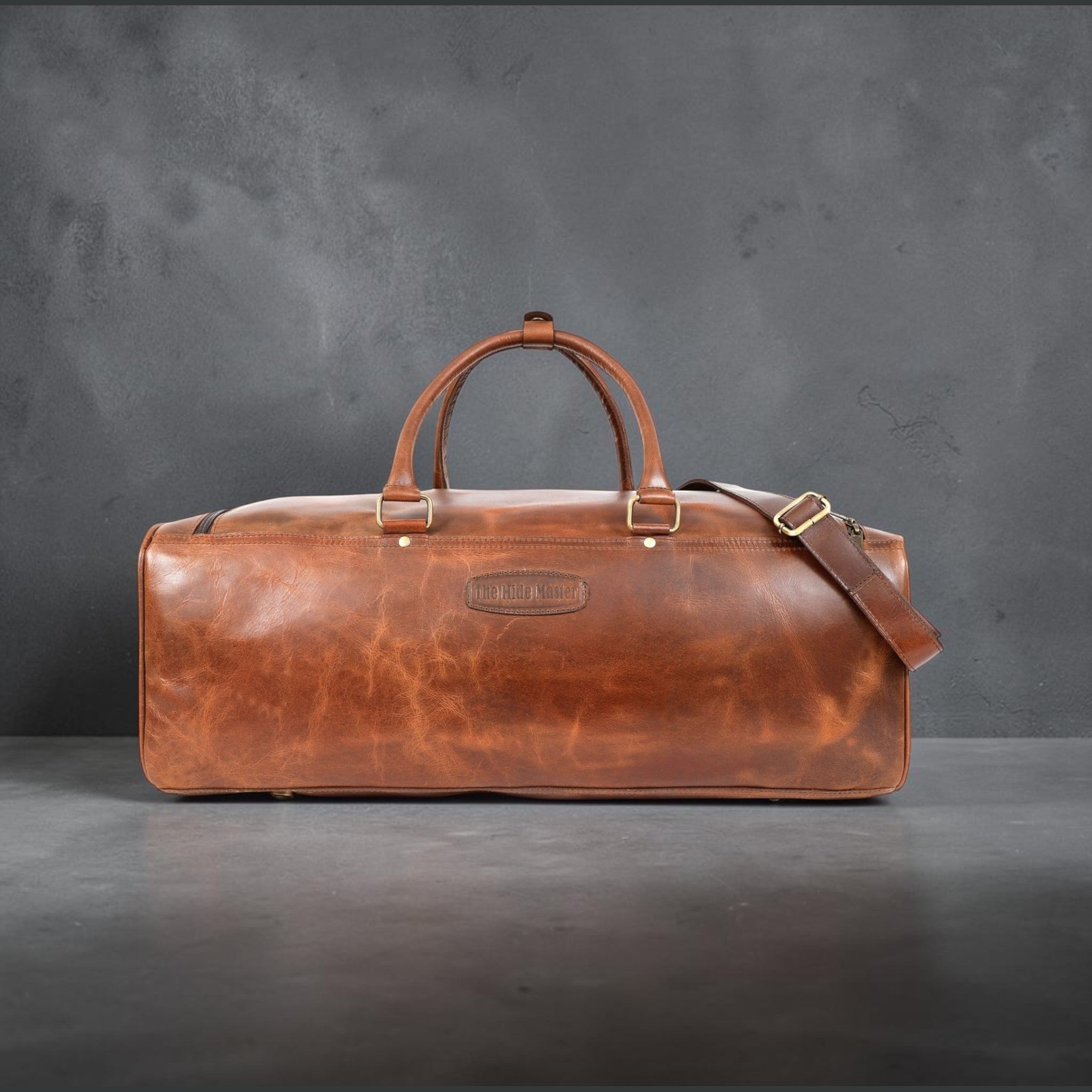 The Hidemaster Aspen Duffle Chef Bag in rustic brown leather, front side view with carry handles and shoulder strap attachment.