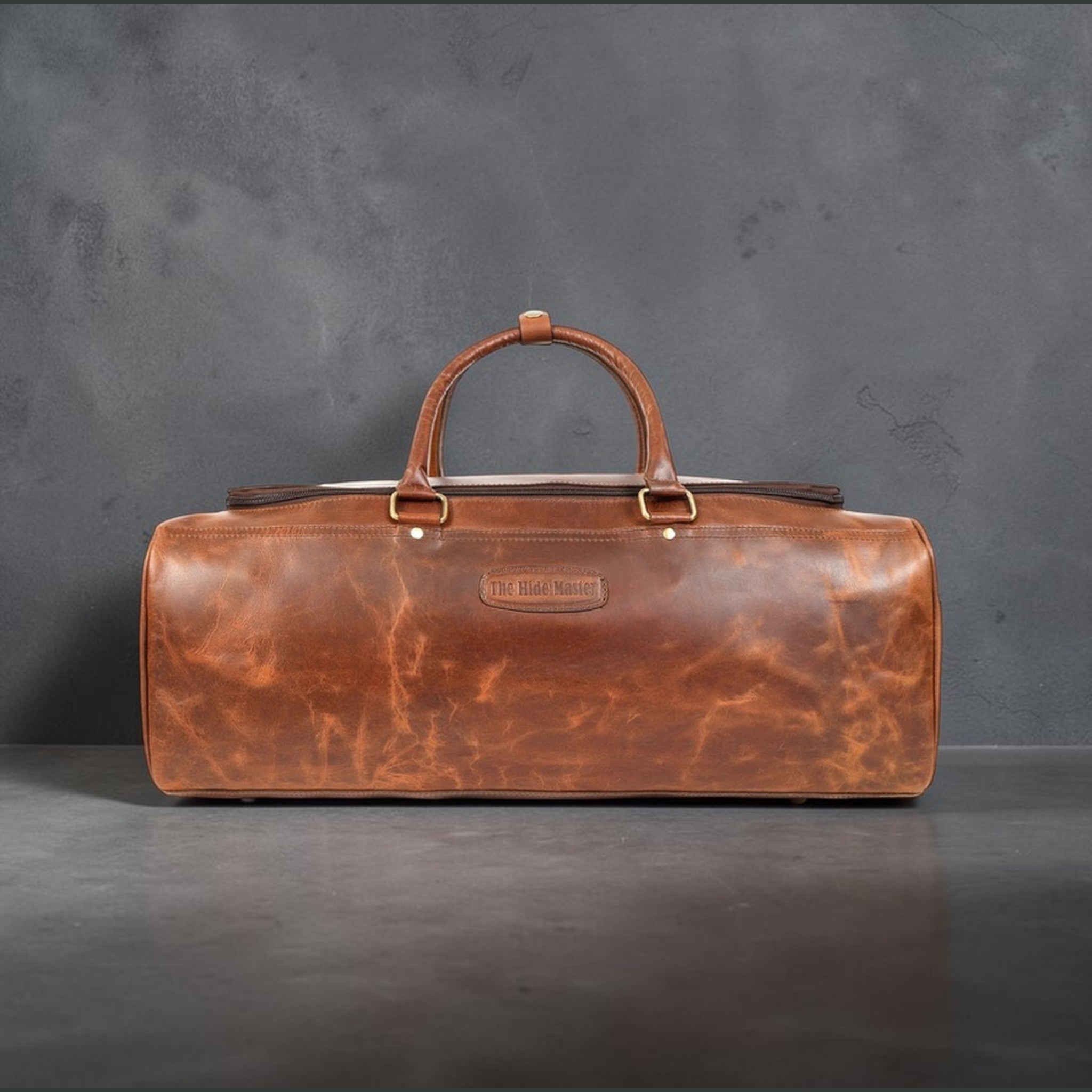 The Hidemaster Aspen Duffle Chef Bag in rustic brown leather, straight side profile with centered handle and logo patch.