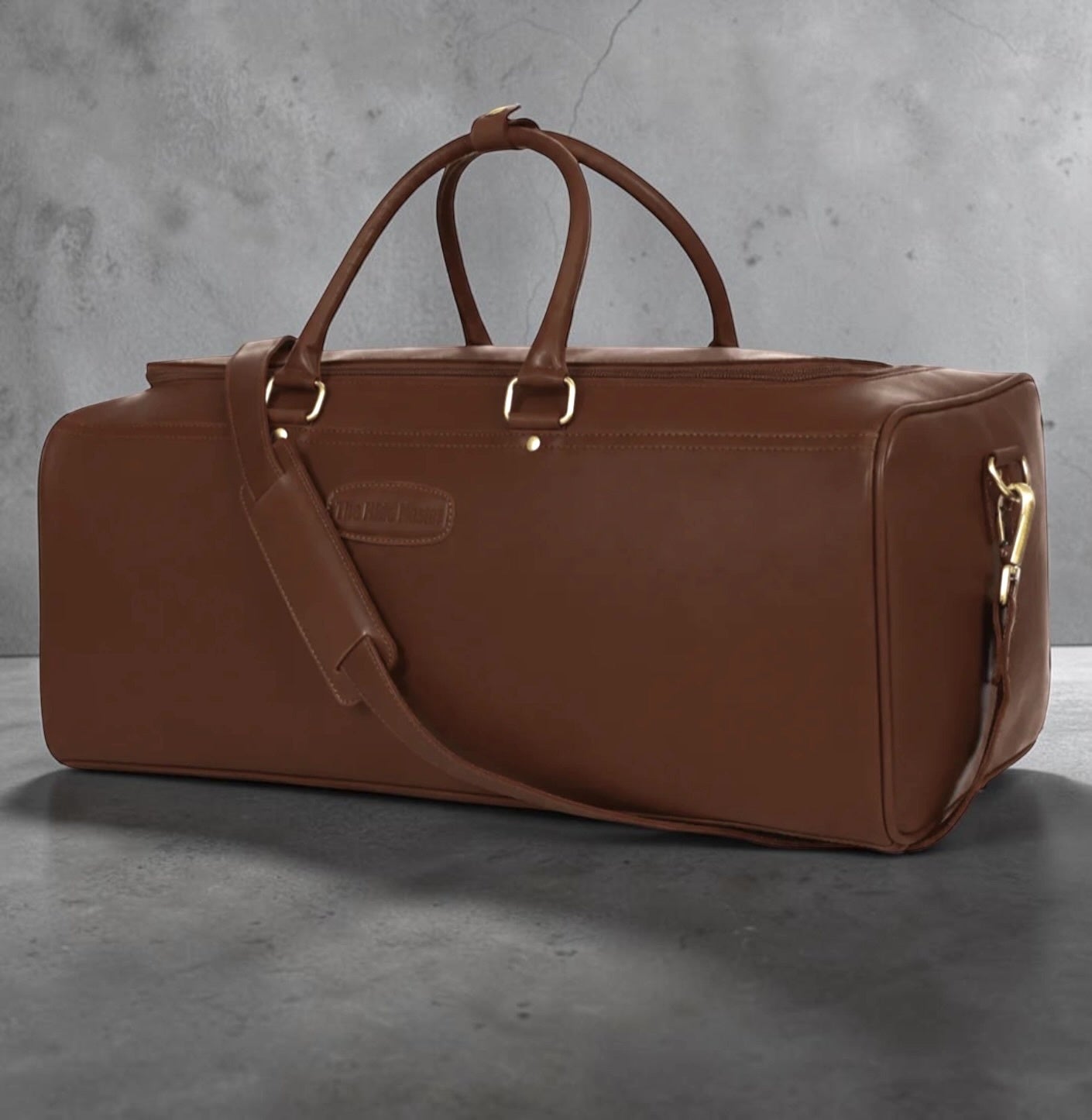 The Hidemaster Aspen leather duffle bag in Brown, featuring premium full-grain leather, rolled carry handles, adjustable shoulder strap, and brass hardware, shown from a front three-quarter angle.