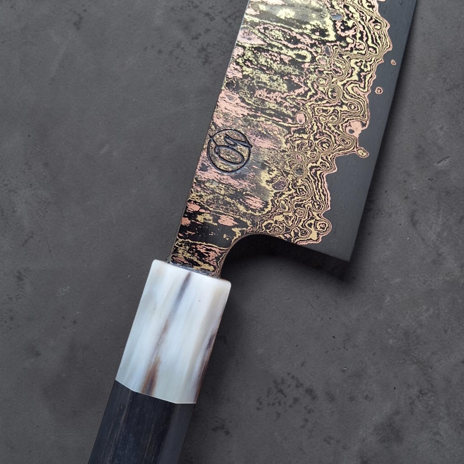 Nahaufnahme der Schmiedemarke von Tu Nguyen, der rainbow Damascus Klinge und der Hornzwinge