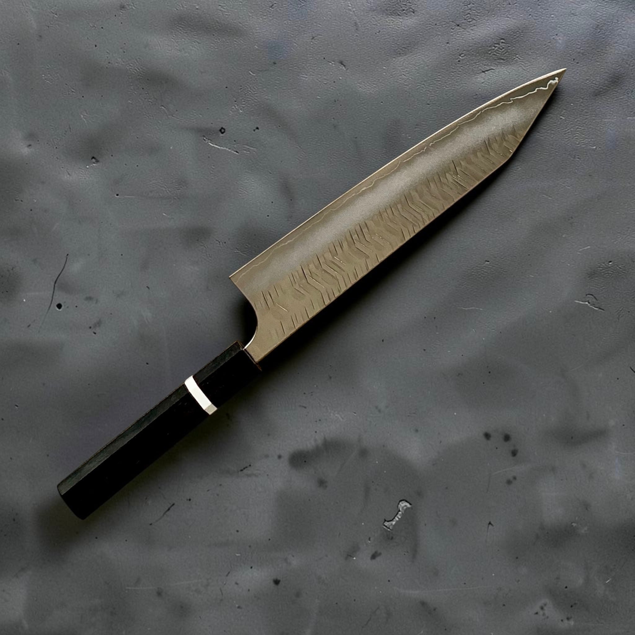 Vista angolata dello Yoshimi Kato SG2 kiritsuke gyuto con finitura martellata a V